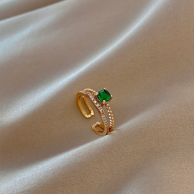 Justerbar ring med smaragd og zirkoner i gull